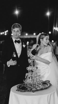 a bride and groom standing next to each other at a table with wine glasses on it