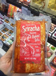 someone holding up a bag of sricha flavored baked joju in a store