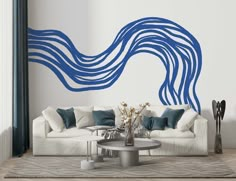 a living room with a white couch and blue wave wall decal on the wall