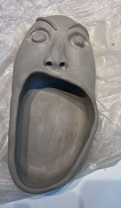 a clay mask is laying on the ground with its mouth open and eyes wide open