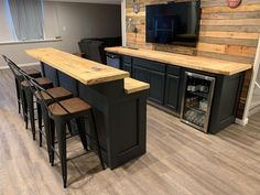 a kitchen with an island and bar stools in front of the tv on the wall