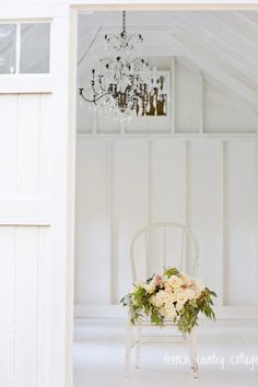 a white chair with flowers on it in front of a chandelier