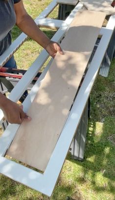 a woman is cutting wood with a pair of scissors on top of the table and another person standing next to her