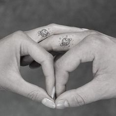 two hands holding each other with small tattoos on their thumb and index finger, in black and white