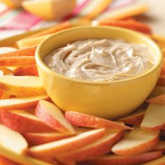 a bowl of dip surrounded by sliced apples