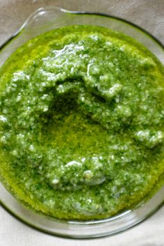 a glass bowl filled with green sauce on top of a table