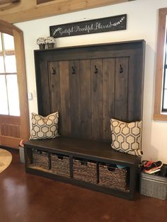 a wooden bench with baskets underneath it in front of a wall mounted coat rack and window