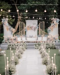 an outdoor ceremony with candles and flowers on the aisle