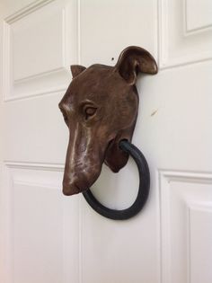 a dog's head mounted to the side of a door with a ring on it