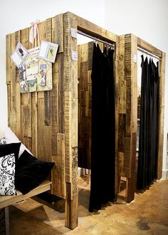 a wooden room divider made out of pallets with clothes hanging on the wall