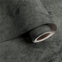 a roll of grey paper on top of a gray surface with a hole in the middle