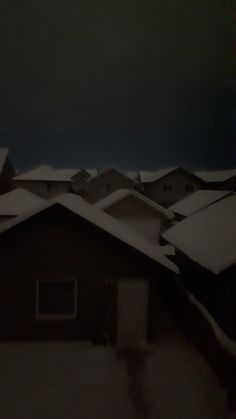 snow covered rooftops and houses in the distance with dark sky behind them on a cold winter day