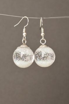 Snow globe earrings Glass globe Flying Snowflakes winter jewelry Christmas gift for women #NewJewelleryStory #Snow #globe #earrings Length: 1/2 Inches; Drop length: 1 Inches; Width: 1/2 InchesSnow globe earrings.Glass globe filled with water and and sequins.It is winter with falling snowflakes.These earrings are a wonderful Christmas present for mom and friends.Glass Sphere 14 mm ( 1/2")Length Drop Earrings: 25mm ( 1" ) Elegant Glitter Dangle Jewelry, Silver Glitter Round Earrings, Round Winter Jewelry Gift, Round Jewelry Gift For Winter, Sparkling Clear Jewelry Gift, Sparkling Clear Jewelry For Gifts, White Sparkling Earrings As A Gift, White Round Christmas Jewelry, Glitter Round Jewelry As Gift