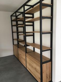 an empty room with shelves and shelving unit in the corner, all made out of wood and metal