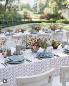 an outdoor table set with plates and place settings