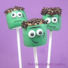 two green monster lollipops with chocolate sprinkles and eyes on them