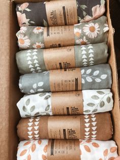 four folded blankets in a box with flowers on them and the bottom one is brown