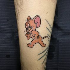 a cartoon character tattoo on the leg of a man's leg, with an orange mouse