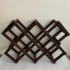 a wooden rack with several pieces of wood stacked on top of each other in front of a white wall