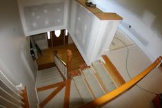 an overhead view of a staircase with wood handrails and white painted walls in the background