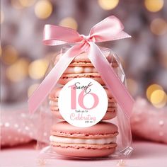 a pink macaroon with a ribbon tied around it's neck and label that says sweet 16 is celebrating