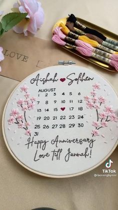 a white plate with pink flowers on it sitting next to some scissors and thread spools