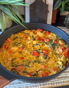 an omelet with tomatoes, spinach and cheese in a pan on a table