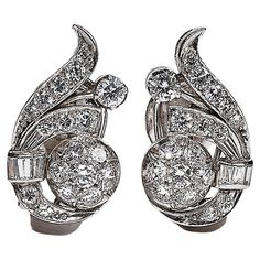 A pair of diamond set scroll earrings each issuing a radiating spray with 21 old brilliant leaves and tied together with a ribbon of baguette cut diamonds, the earrings measures between 21mm and 12mm, rub-over and claw set in silver as typical for the period. Estimated total diamond content for both earrings is 1.8 – 2,00 ctw, assessed as G - I color and SI clarity. Clip and post fittings. In very good condition. Some minimal fretting to a few of the stones. Weight 6.7grams. 1950s was an inspiri Antique Diamond Earrings, Baguette Cut Diamond, Antique Diamond, Diamond Set, Baguette Cut, Social Events, Hollywood Glamour, Jewelry Earrings Studs, Cocktail Party