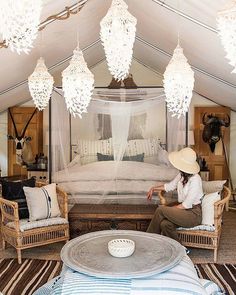 a woman sitting on a chair in front of a bed with mosquito netting over it