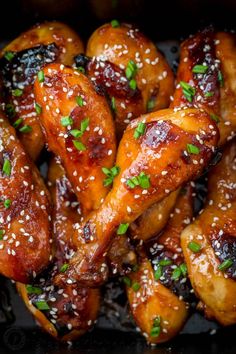 chicken wings covered in sesame seeds and garnished with parsley on a black plate