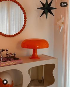 an orange lamp is sitting on top of a white shelf in front of a mirror