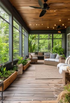 a porch with lots of windows and plants on the floor, along with couches