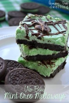 mint oreo melt squares are stacked on top of each other, with chocolate cookies in the background