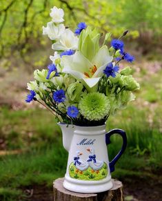 a blue and white vase with flowers in it sitting on top of a tree stump