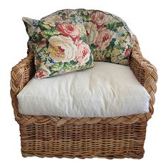 a wicker chair with two pillows on it's back and one pillow in the middle