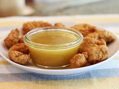 a white plate topped with tater tots next to a small bowl of dipping sauce