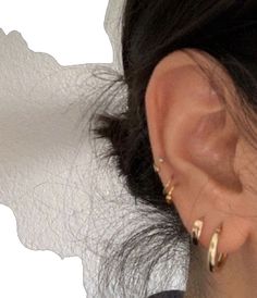 a close up of a person's ear with two gold hoop earrings on it