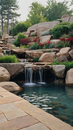 there is a small waterfall in the middle of this pool that's surrounded by large rocks