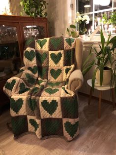 a green and white blanket sitting on top of a chair next to a potted plant