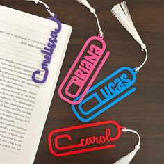 three bookmarks that are sitting next to an open book on a table with tassels