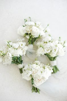 wedding bouquets laid out on the floor with white flowers and greenery around them