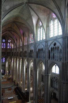 the interior of a large cathedral with pews and stained glass windows on both sides