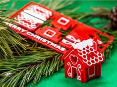 a red house ornament sitting on top of a pine tree next to a green background