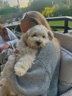 a woman holding a white dog in her arms