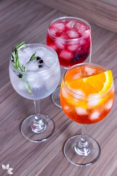 three glasses filled with different types of drinks on top of a wooden table and the words receitas de gin tonica written in spanish