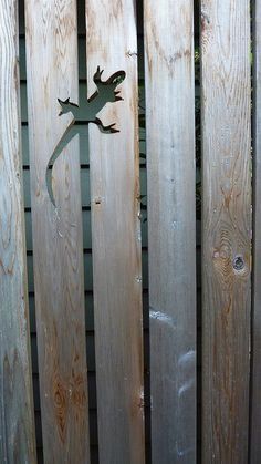 a metal lizard on the side of a wooden fence