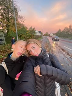 two young women taking a selfie on the side of the road at sunset or dawn