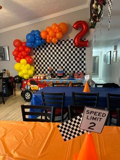 a birthday party with balloons and race cars on the wall, checkered table cloths