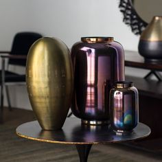 three vases sitting on top of a table next to each other in front of a mirror