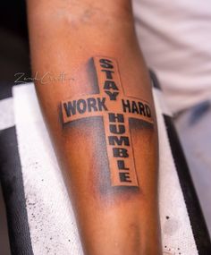 a man with a cross tattoo on his arm that says work hard, maybe jesus christ